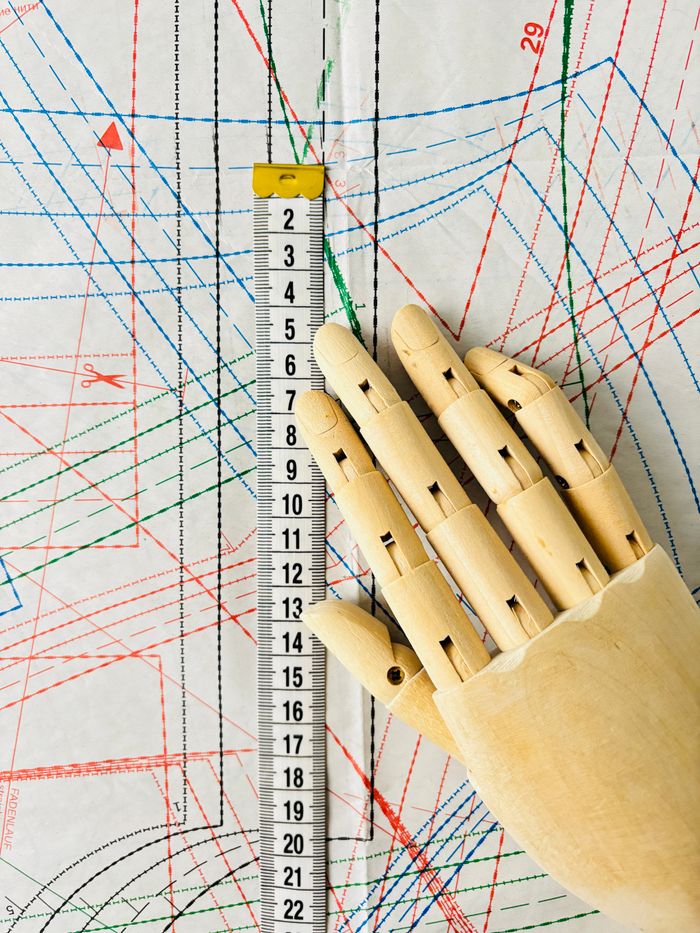 Artistic display of a wooden mannequin hand measuring sewing patterns, perfect for creative projects.